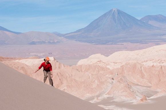 Rapaz descendo de prancha as dunas do Vale da Morte, no Deserto do Atacama