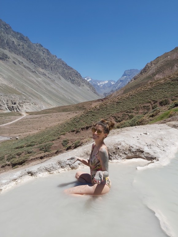 mulher em area termal no chile, com montanhas ao fundo em dia ensolarado