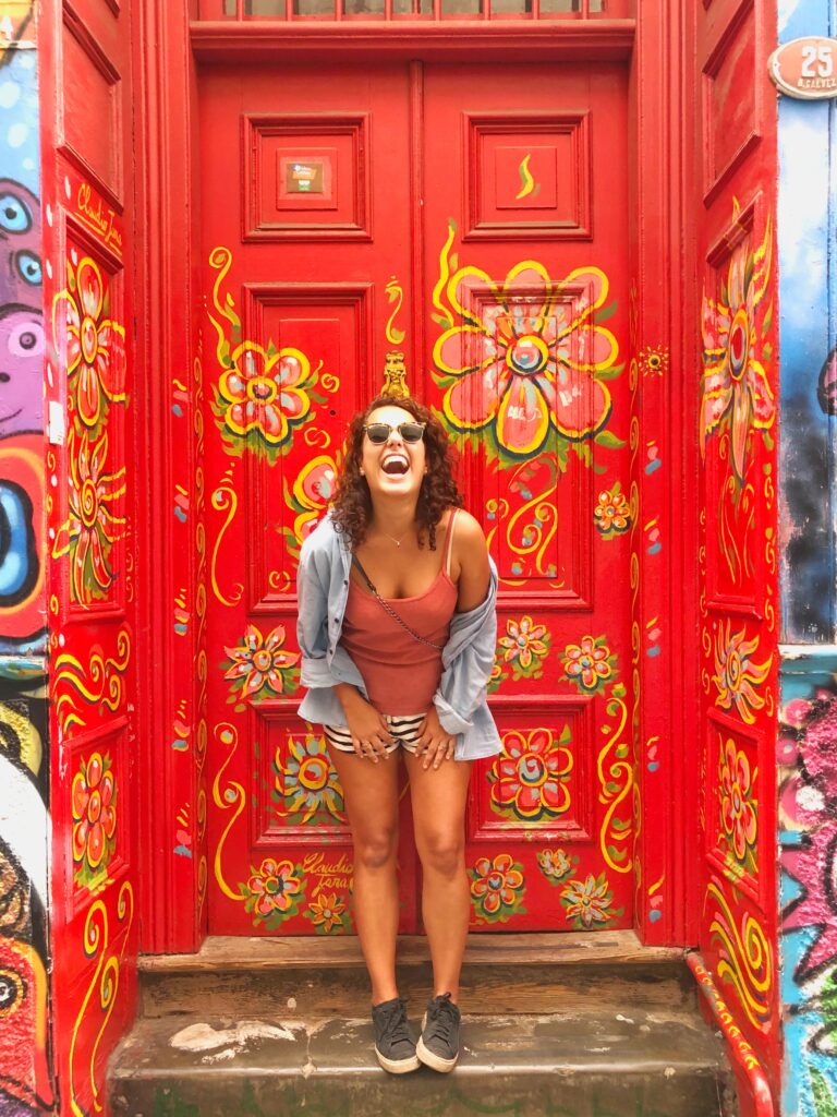 mulher em frente a uma porta colorida em Valparaíso, Chile.