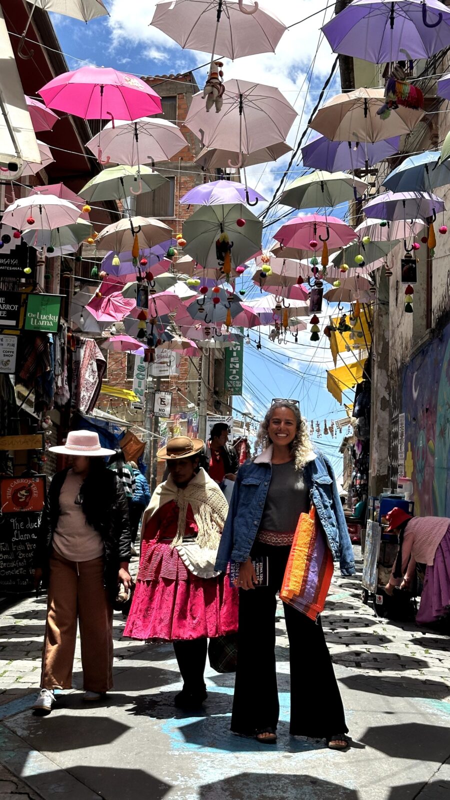 pessoas em uma rua de vilarejo em la paz, bolivia, e sombreados por vários guarda chuvas suspensos