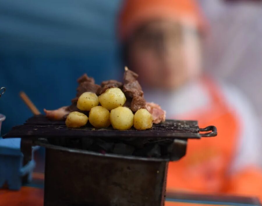 Barraca de anticuchos em La Paz, na Bolívia, com carne e batatas em uma chapa