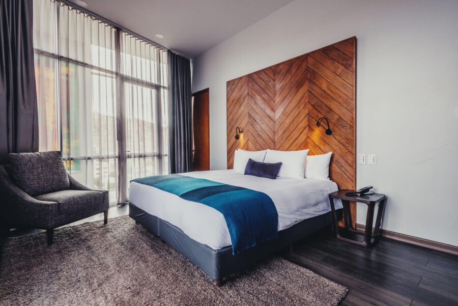 quarto de luxo com uma grande janela coberta por uma cortina, uma cama casal e uma moldura