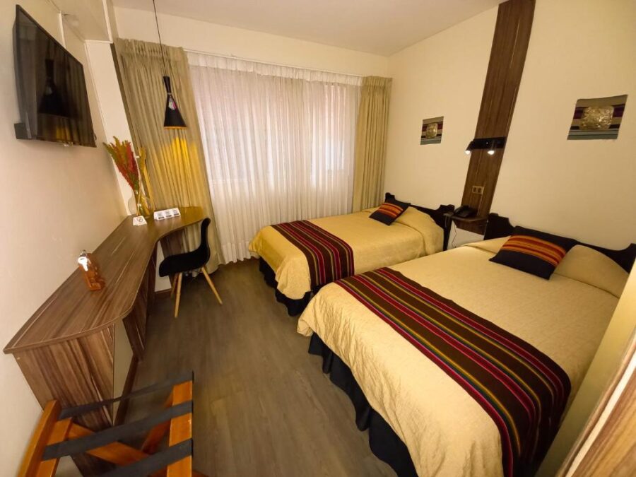 quarto com duas camas de casal, uma janela fechada e varios objetos decorativos de madeira