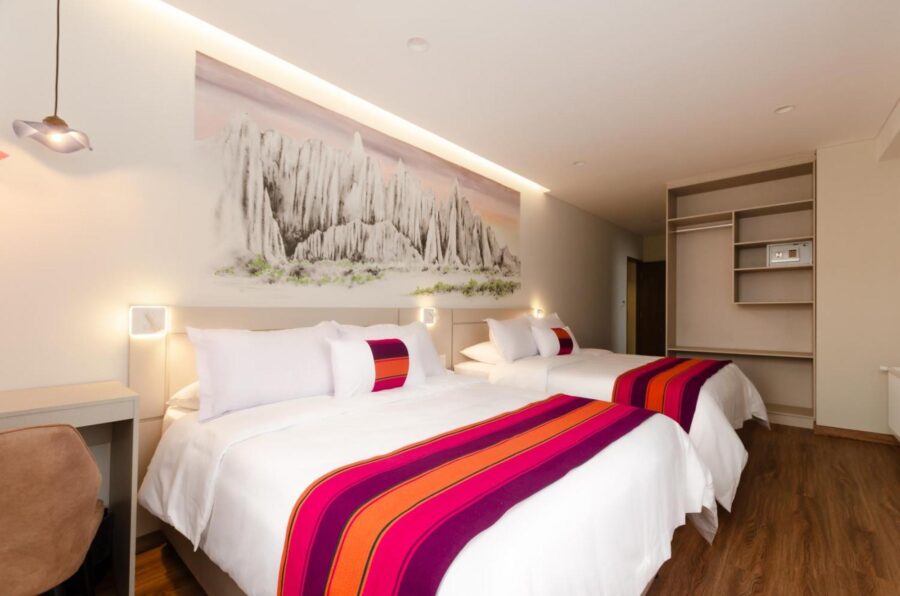 quarto com duas camas casal e um grande quadro na parede