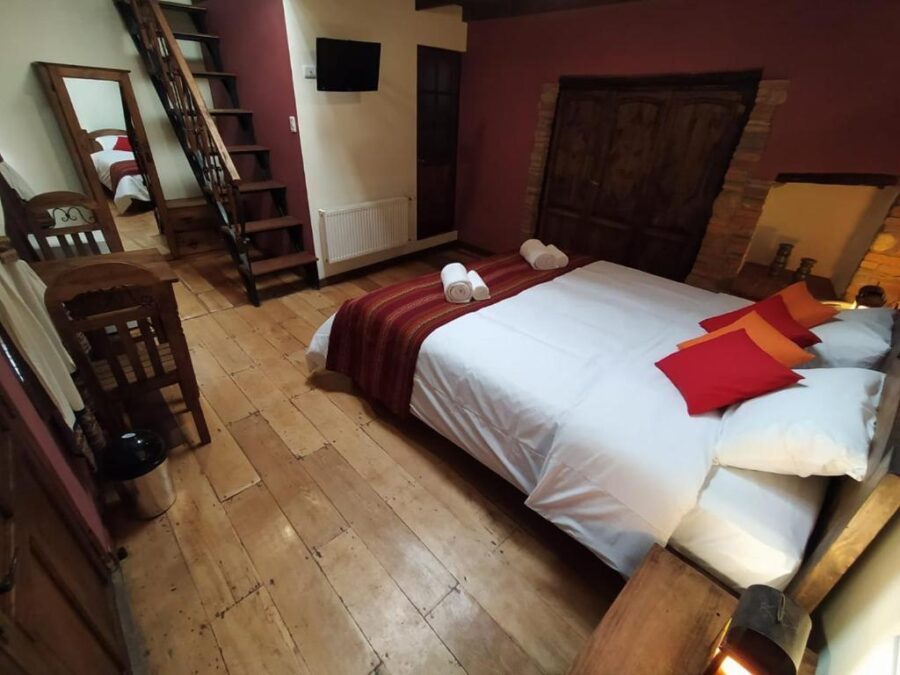 quarto rustico com cama, uma escada e piso de madeira