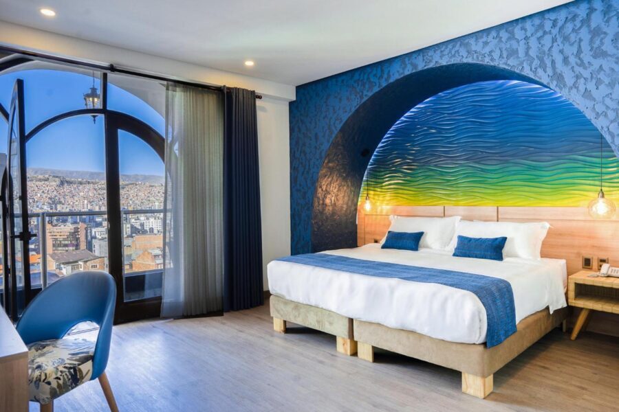 quarto com cama casal, enfeites e uma janela panoramica