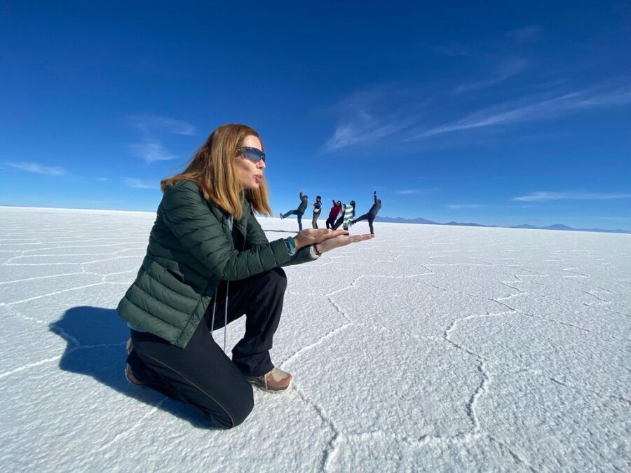 Turista fazendo foto criativa com efeito de perspectiva no Salar de Uyuni durante a estação seca.