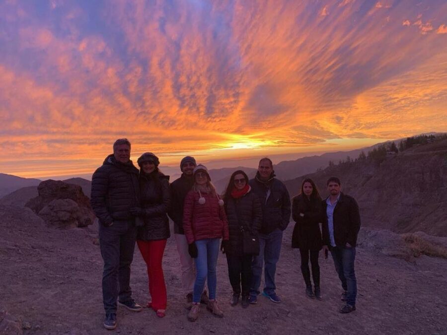 Grupo de turistas assistindo ao pôr do sol em região andina durante viagem por Santiago, no Chile
