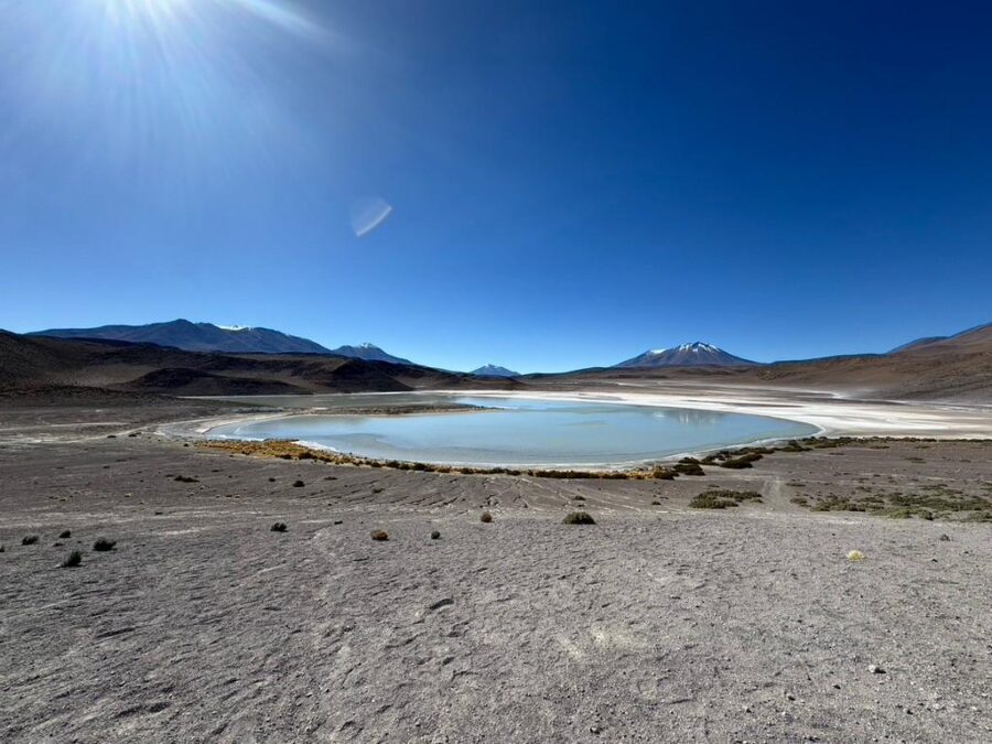 Salar de Uyuni na Bolívia com lagoa rasa cercada por montanhas e céu azul intenso