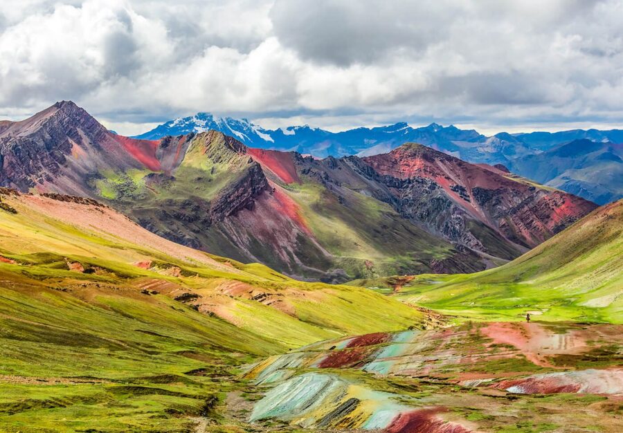 Vale andino com montanhas coloridas próximas à Montanha de 7 Cores, com vegetação verde e picos ao fundo
