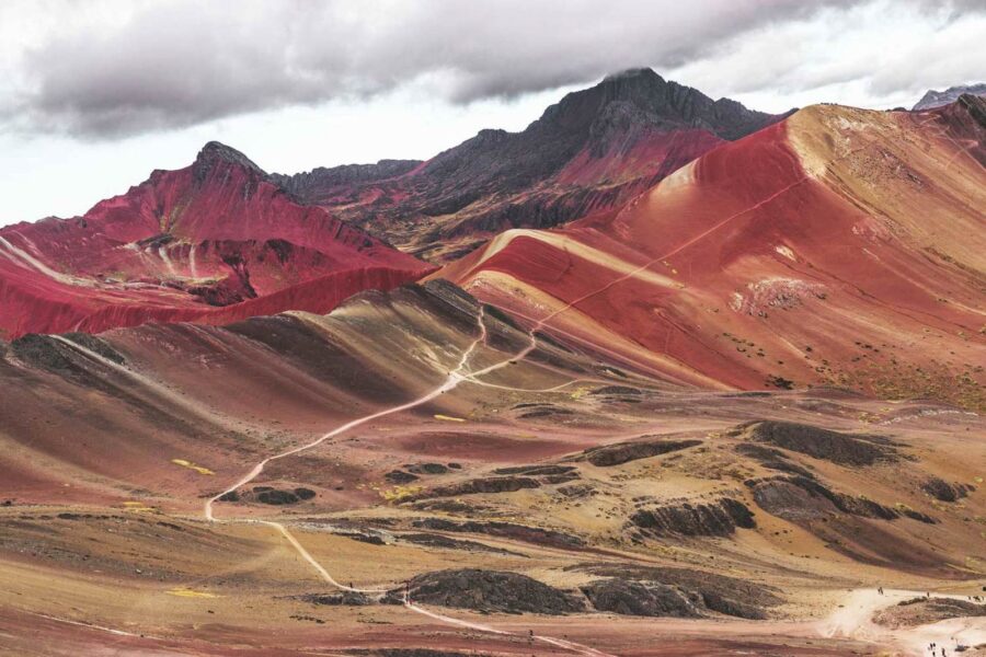 Vale andino com montanhas coloridas próximas à Montanha de 7 Cores, com vegetação verde e picos ao fundo