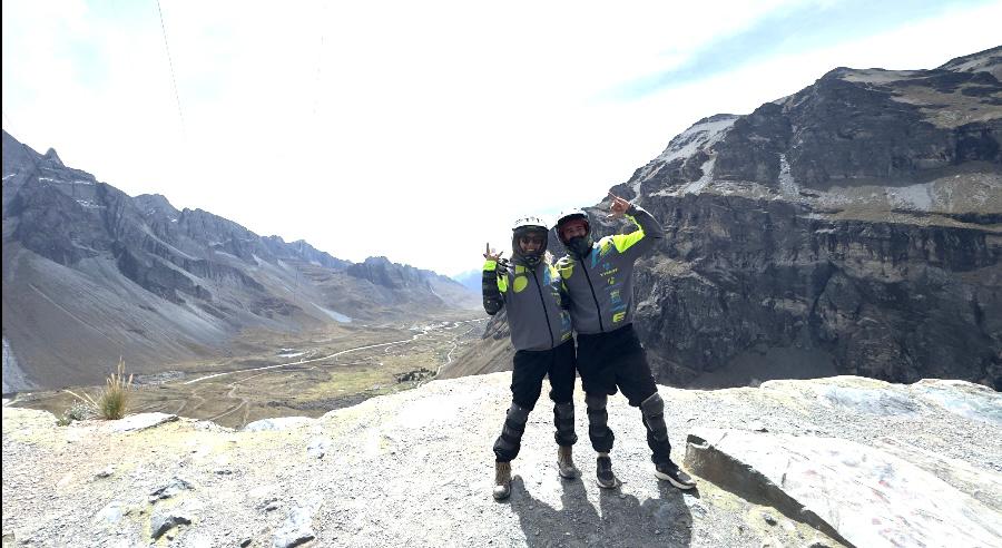 Duas pessoas com roupas de proteção posam em mirante de montanha em La Paz