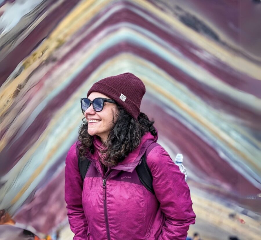 Mulher sorrindo na Montanha de 7 Cores, perto de Cusco, com formações coloridas ao fundo
