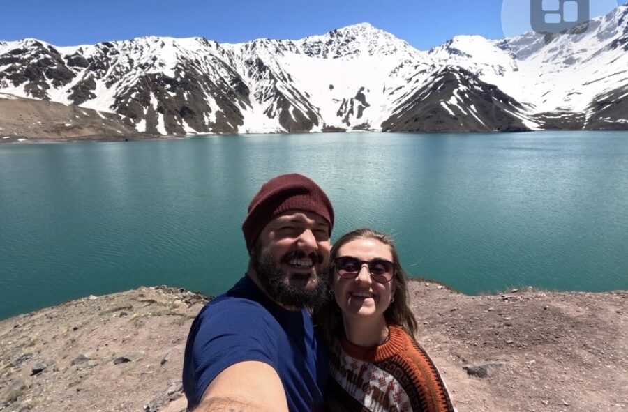 Casal em lua de mel na América do Sul, em frente a um lago azul cercado por montanhas nevadas