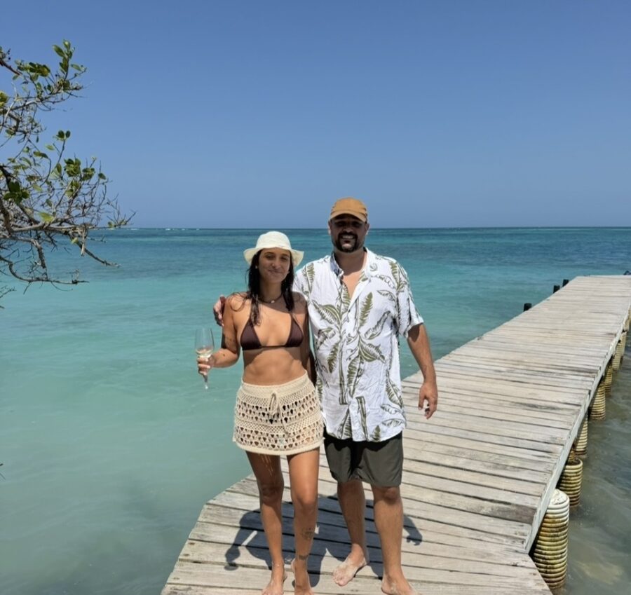 Casal posando em píer de madeira cercado pelo mar azul de Cartagena, aproveitando um roteiro romântico em Cartagena com paisagens tropicais.