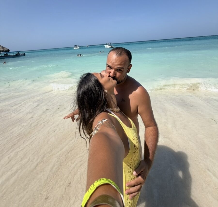 Casal se beijando em uma praia de águas cristalinas em roteiro romântico em San Andrés, registrando o momento em uma selfie com o Mar das Sete Cores ao fundo, em um cenário romântico típico do Caribe colombiano.