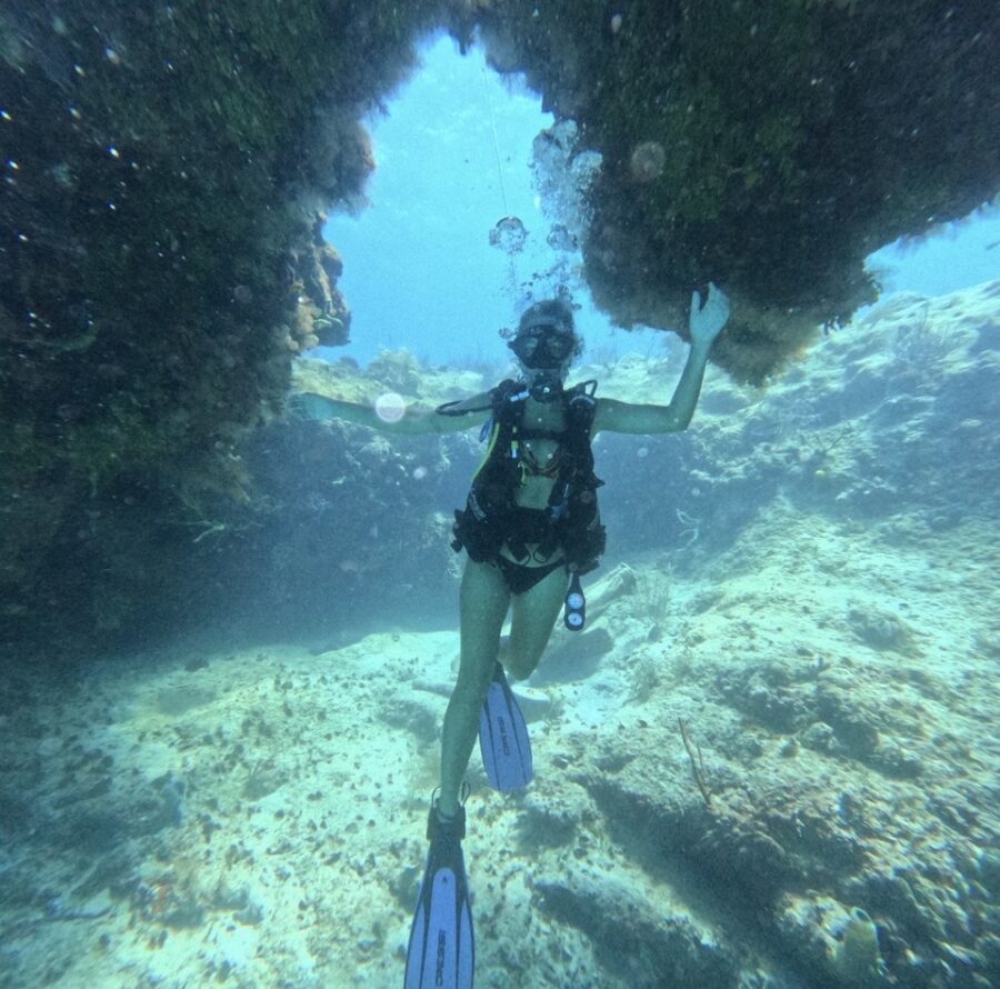 Mergulhadora explorando formações rochosas e recifes em San Andrés, destino caribenho famoso por suas águas cristalinas.