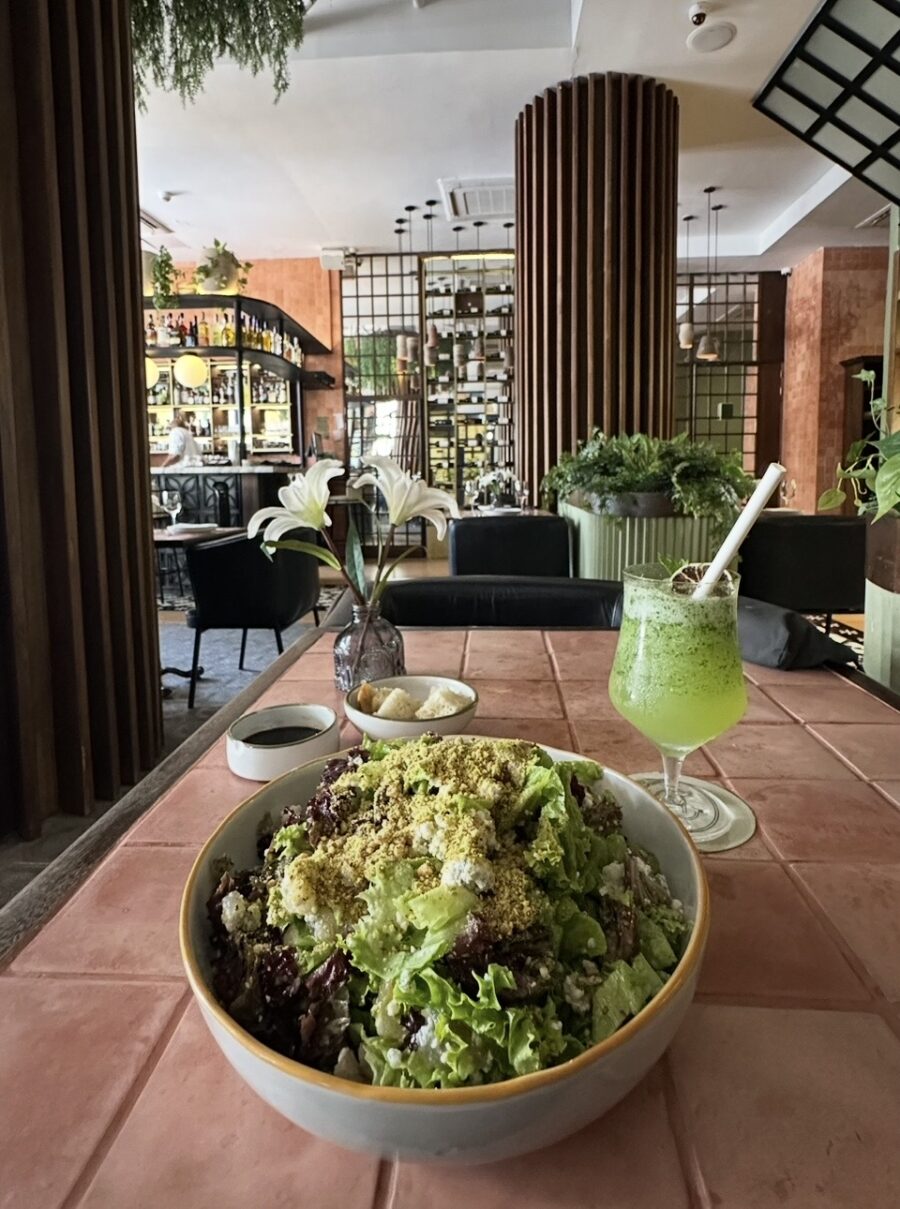 Salada fresca acompanhada de uma bebida verde servidas em um restaurante moderno e aconchegante, representando a diversidade da gastronomia em San Andrés.