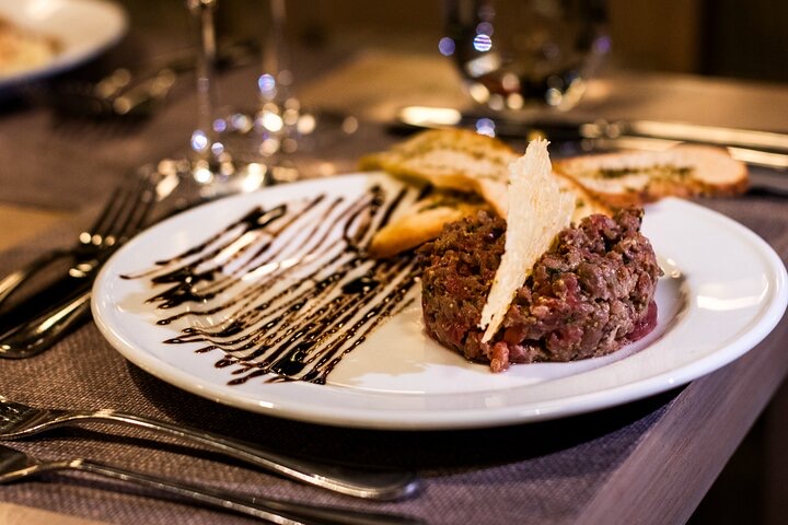 Prato sofisticado com carne tartare e decoração de chocolate em restaurante, representando experiências gastronômicas em Santiago