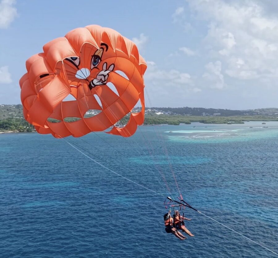 Parasail em San Andrés com duas pessoas suspensas sobre o mar azul-turquesa, usando equipamentos de segurança e contemplando a paisagem do Caribe
