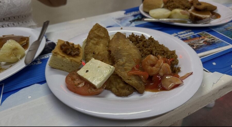 Prato de peixe empanado, arroz, camarão ao molho, fatia de bolo e queijo em um restaurante, representando a diversidade da gastronomia em San Andrés