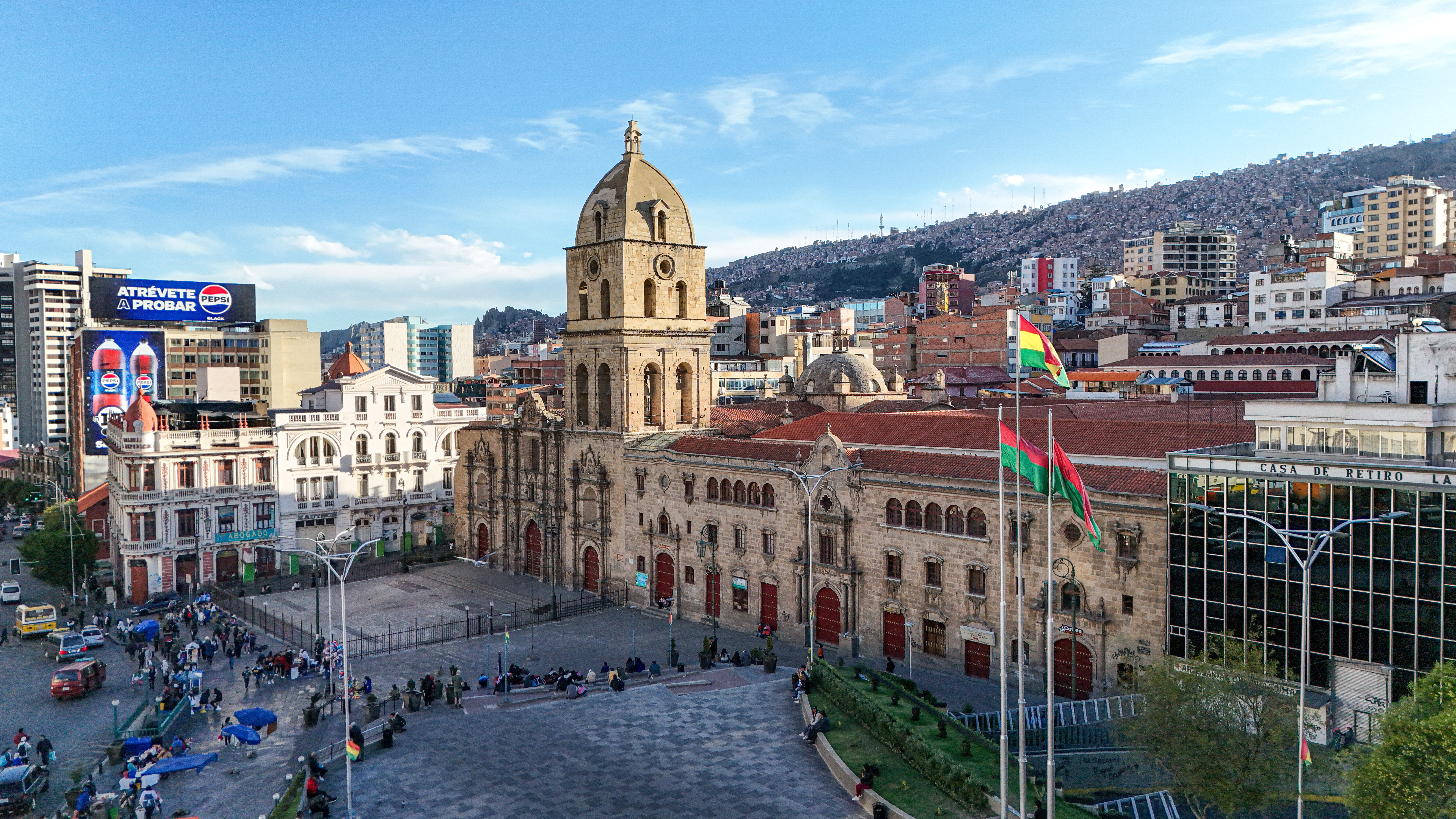 Uma vista aérea da Plaza San Francisco em La Paz, Bolívia, com a sua basílica colonial histórica e a cidade subindo pelas encostas das montanhas ao fundo, um destino urbano para viajar em feriados ou férias