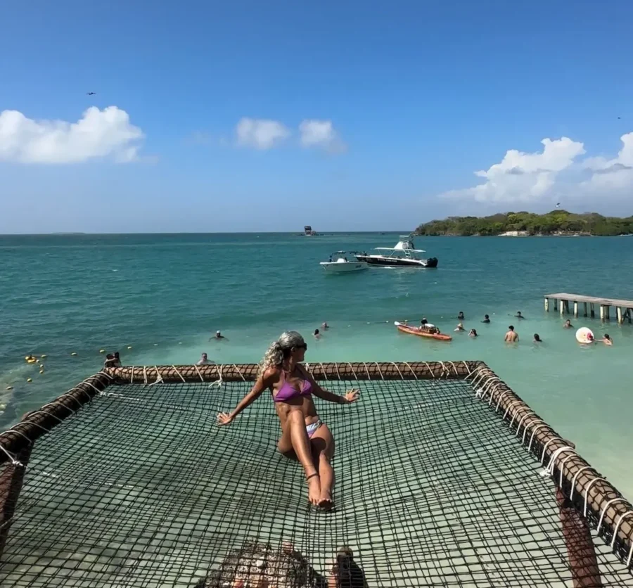 Uma mulher de biquíni relaxa em uma grande rede suspensa sobre o mar turquesa, em um dos beach clubs em Cartagena