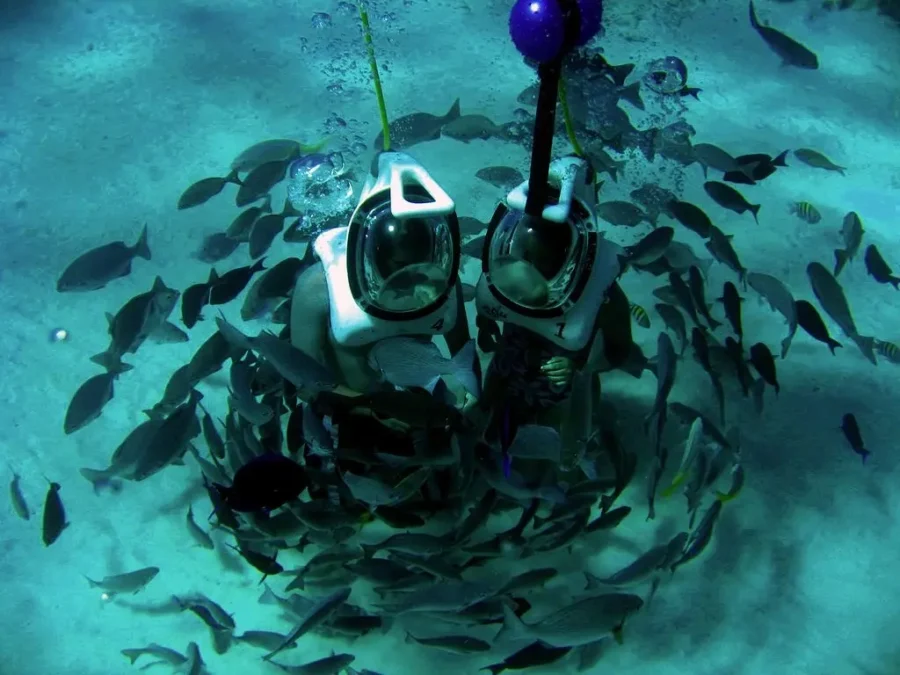Turista participando da experiência de Aquanautas em San Andrés no fundo do mar, conectado a um barco na superfície