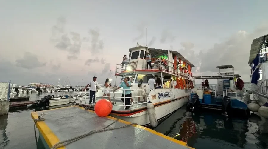 Noche Blanca ou Yate Rumba em San Andrés: Pessoas embarcando em um barco de festa de dois andares em uma marina de San Andrés durante o crepúsculo