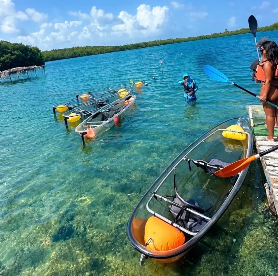 Vista de caiaques transparentes ancorados e pessoas na água cristalina em dia ensolarado com a Ecofiwi em San Andrés