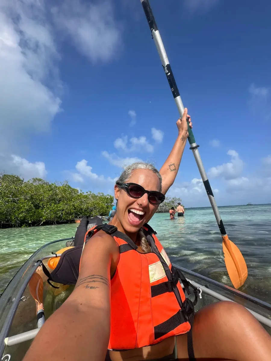 Mulher sorridente segurando o remo para o alto, fazendo selfie em caiaque transparente durante experiência da Ecofiwi em San Andrés