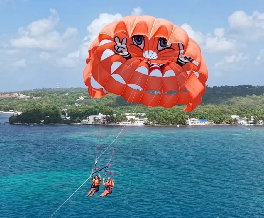 Turistas praticando parasailing sobre o mar azul em um destino caribenho durante férias com roteiro na América do Sul