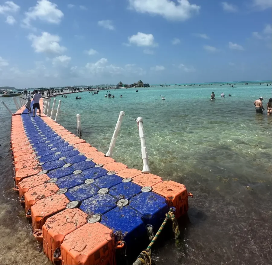 Mega Tour Johnny Cay e Aquário com passarela flutuante sobre águas rasas e cristalinas, cercada por visitantes e pelo mar azul-turquesa de San Andrés