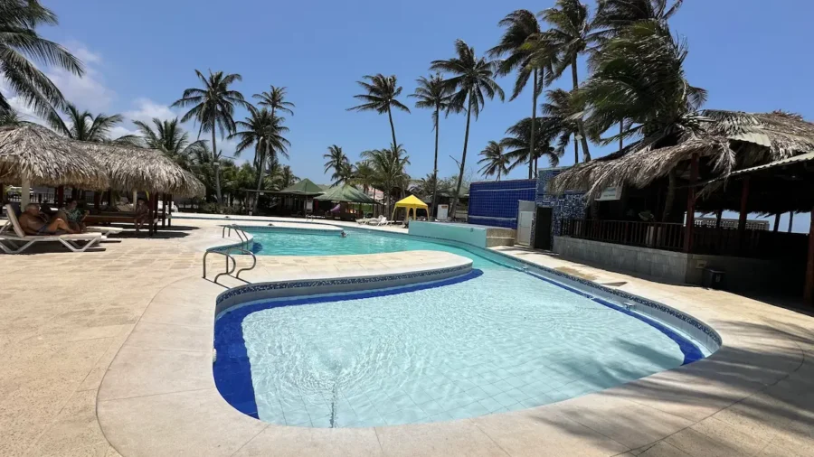 Piscina ao ar livre cercada por quiosques de palha e coqueiros, em uma área de lazer visitada durante o passeio ao Vulcão Totumo em Cartagena
