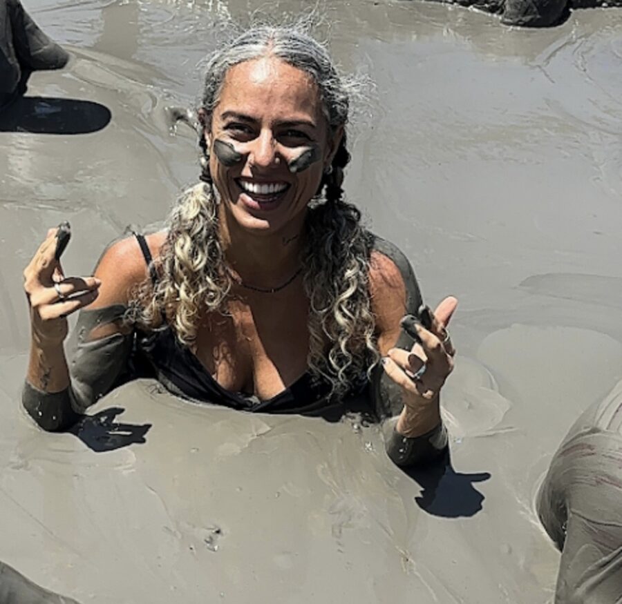Mulher aproveitando o banho de lama durante a experiência no Vulcão Totumo em Cartagena, com o corpo imerso na lama vulcânica